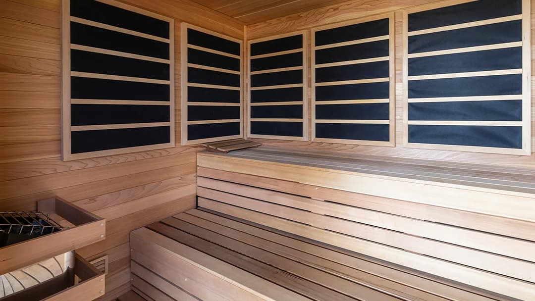 A custom timber sauna with broad benches and infrared panels.