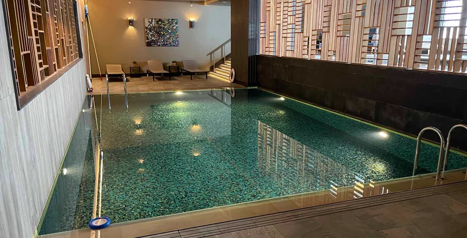 An indoor spa pool with mosaic tiles and timber lattice screens.