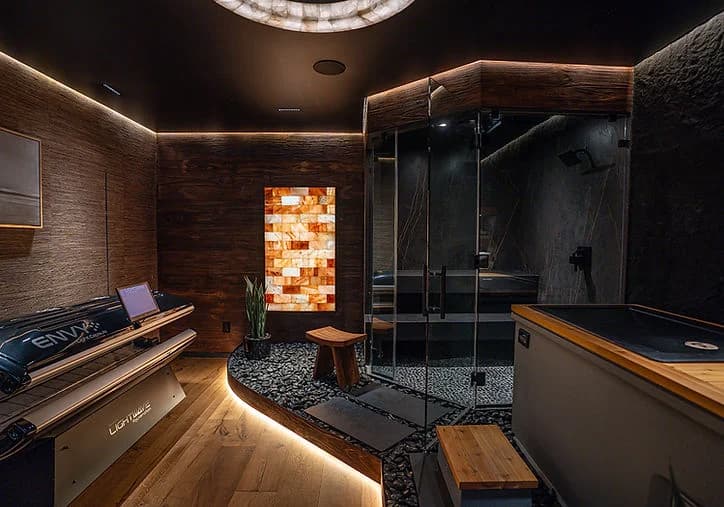 A dark timber sauna with tiered benches and a glass-front heater enclosure.